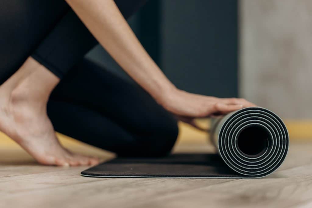 Woman rolling out exercise mat at home.