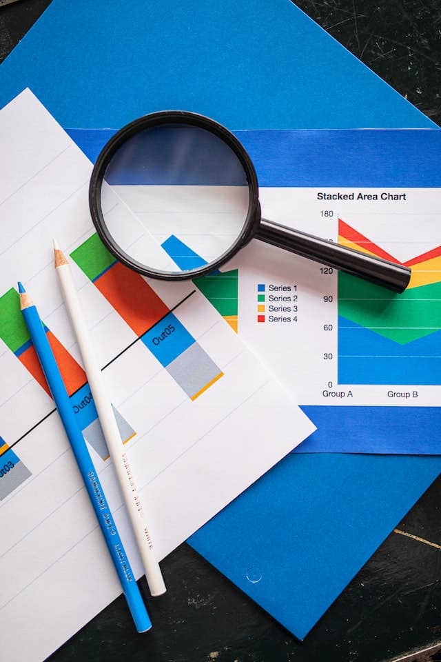 A magnifying glass, colored pencils, and graphs that signify the concept of market research that is necessary for niche consultants to understand.