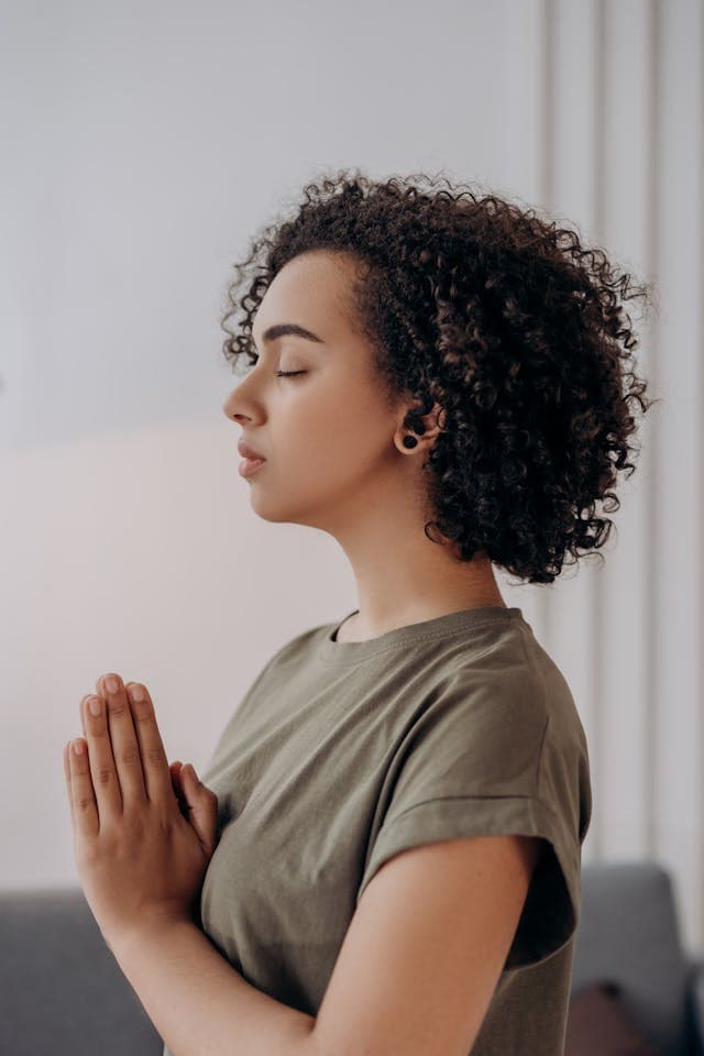 An independent consultant CRA who is woman upright with hands in front of her in a prayer-like pose and with her eyes closed as she enhances her work-life balance.