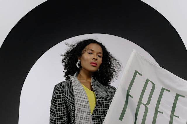 Shoestring woman independent consultant stands behind a sign with the word free.